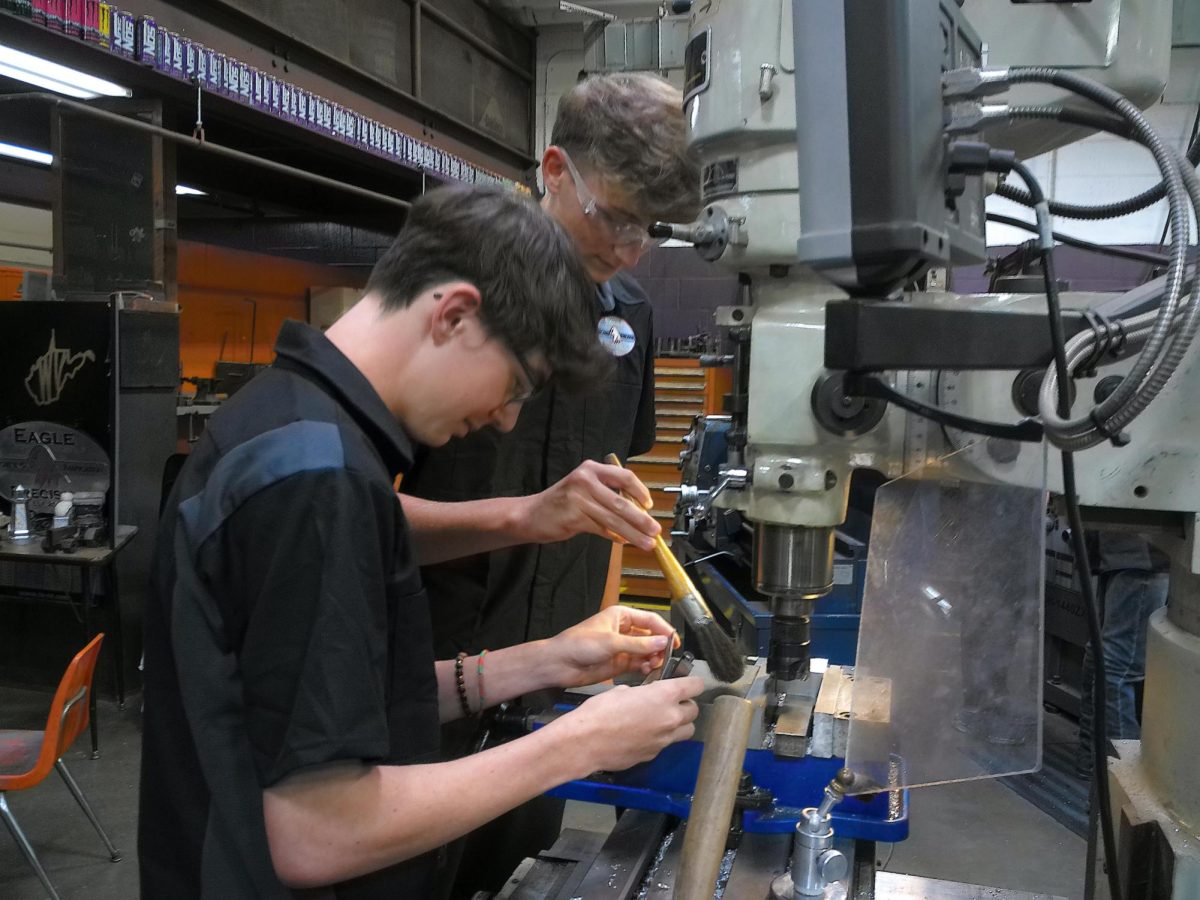 Students are using  a CNC milling machine to carve out their project 