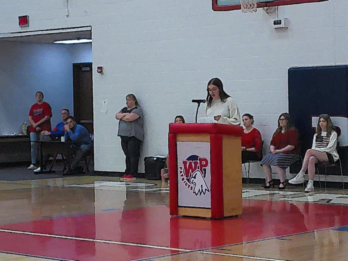 Grace Robertson-VIllamagna, the Vice President of the Speech and Debate Team, reads the history of taps to the crowd along with other team members who taught the history of Veterans Day and read poetry about service.