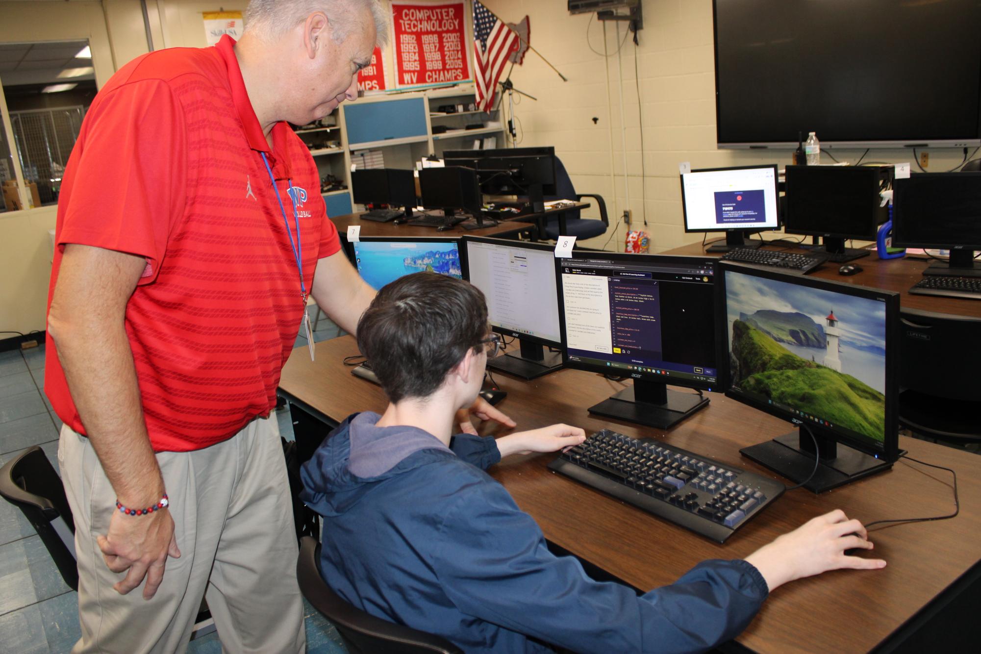 Mr. Schehl and a student use technology in his coding program.