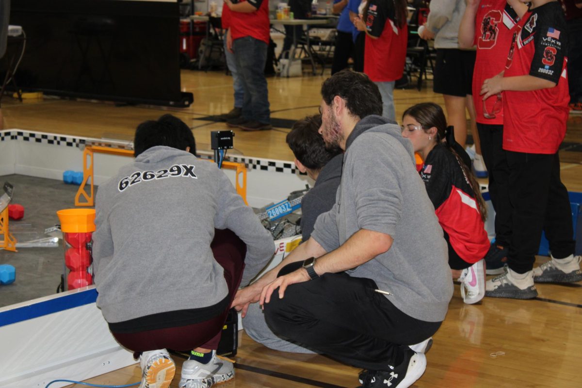 Two team mates from a Wheeling Park team working to fix their robot in a match.