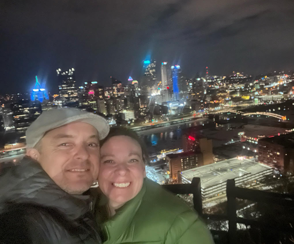 Ryan Wall (left) with his wife Shannon Wall (right) taking a picture in front of the skyline of Pittsburgh, Pennsylvania. 