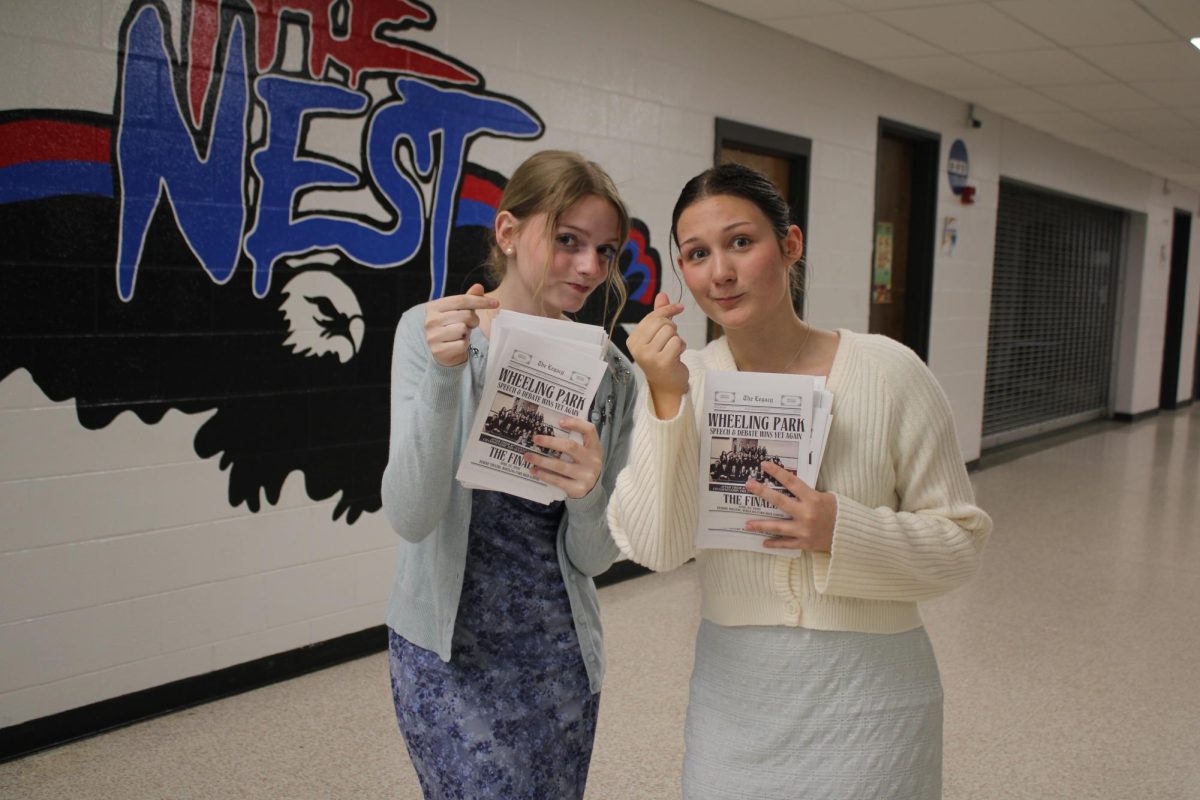 Ella Wheeler and Emma Seibert greet families with programs. 